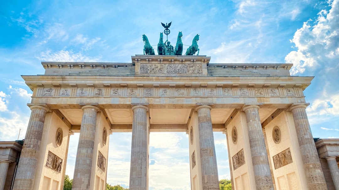 a large stone building with columns and statues on top with Brandenburg Gate in the background